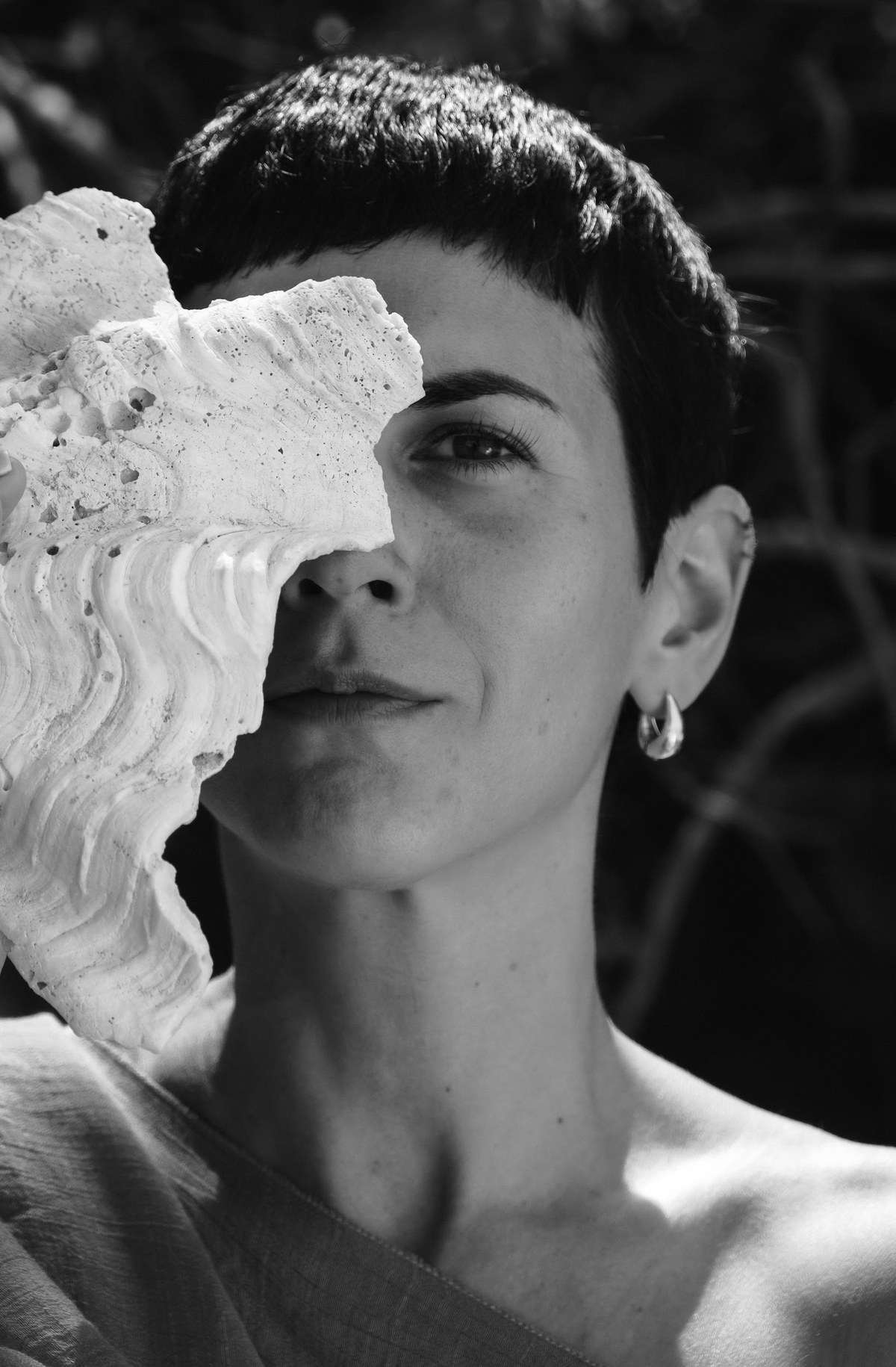 Black and white portrait of Aalia holding a shell beside her face