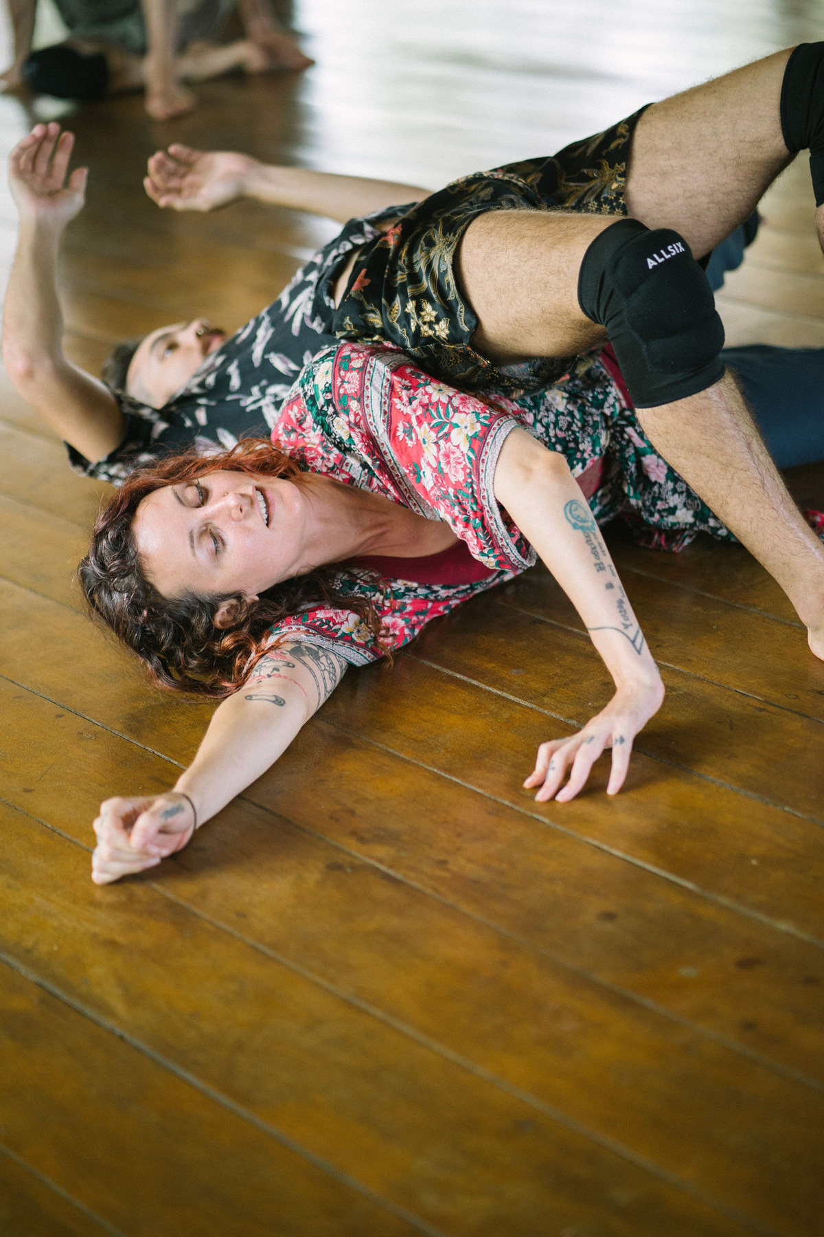 A dancer in a floral top moving across a wooden floor