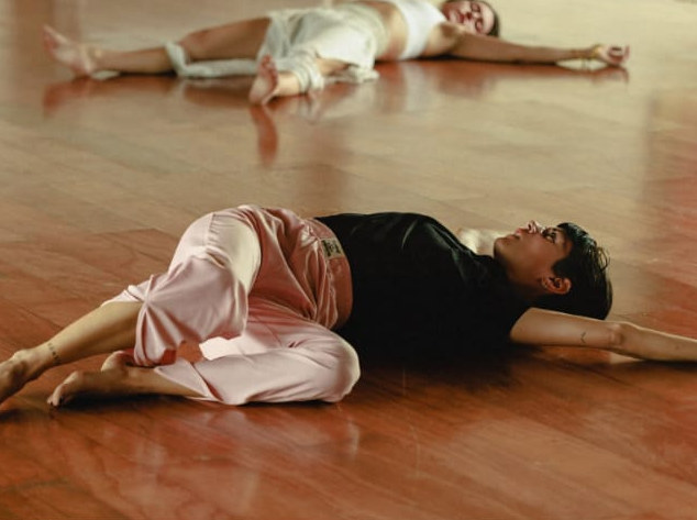 Aalia lying on a warm wooden studio floor during floorwork