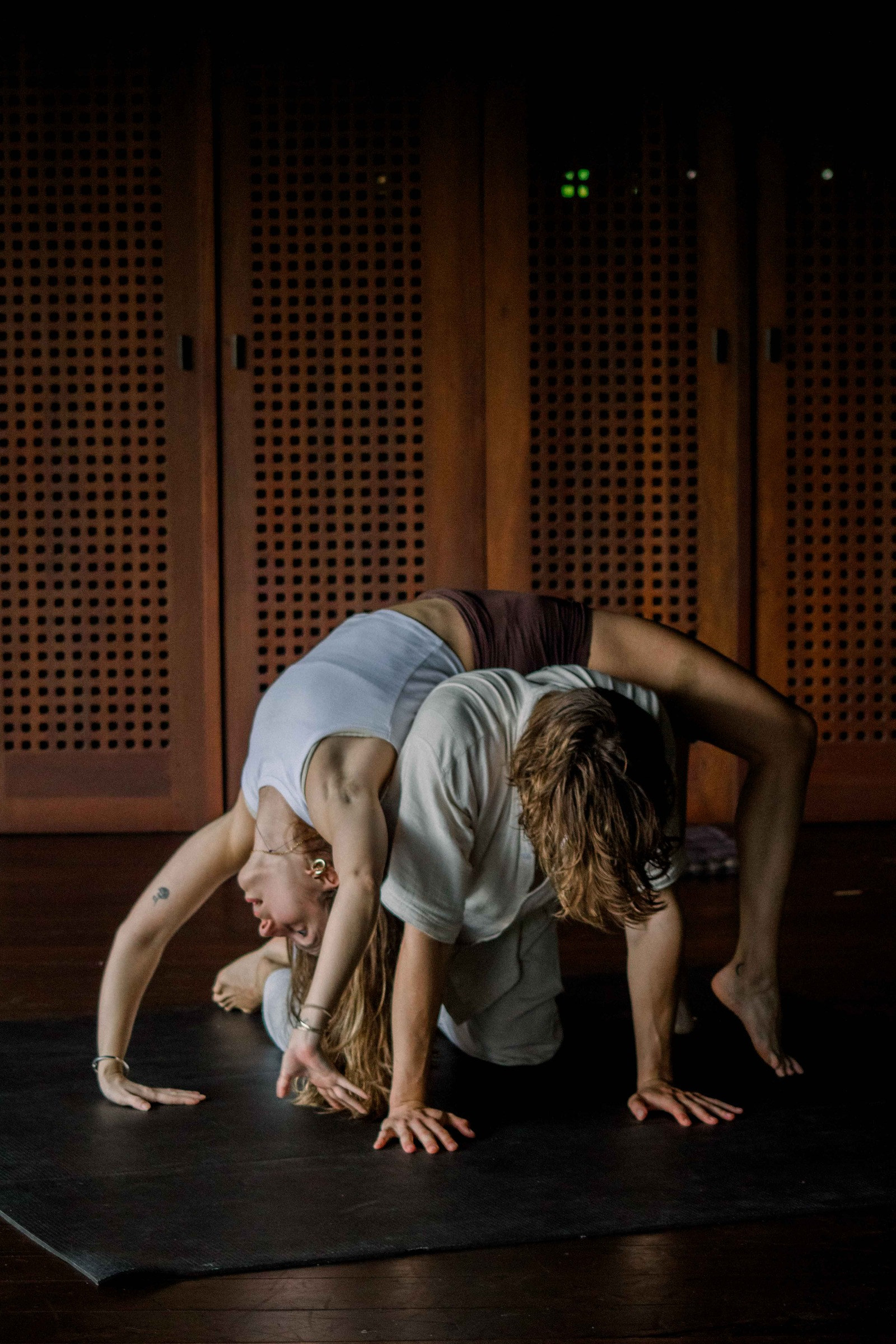 Dancers rolling over each other in a dark studio