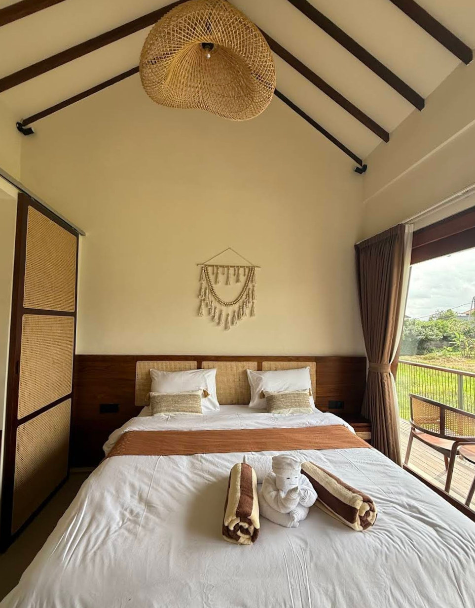 A modern guest room at Rasa Yoga with a rattan headboard and garden view