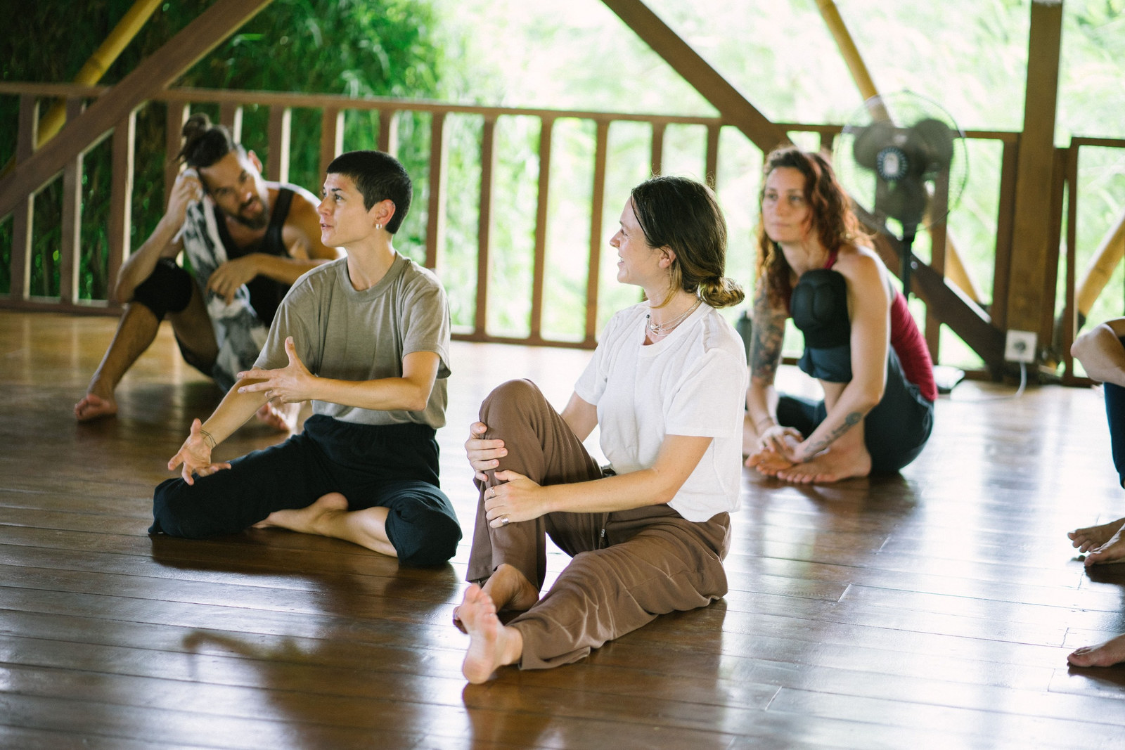 Aalia demonstrating to seated students on a wooden studio floor