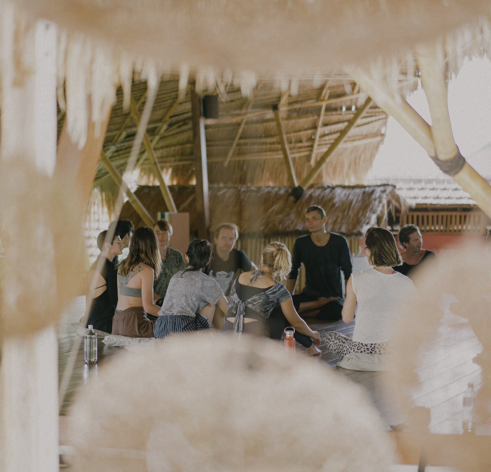 A Momentum workshop group gathered under a thatched roof